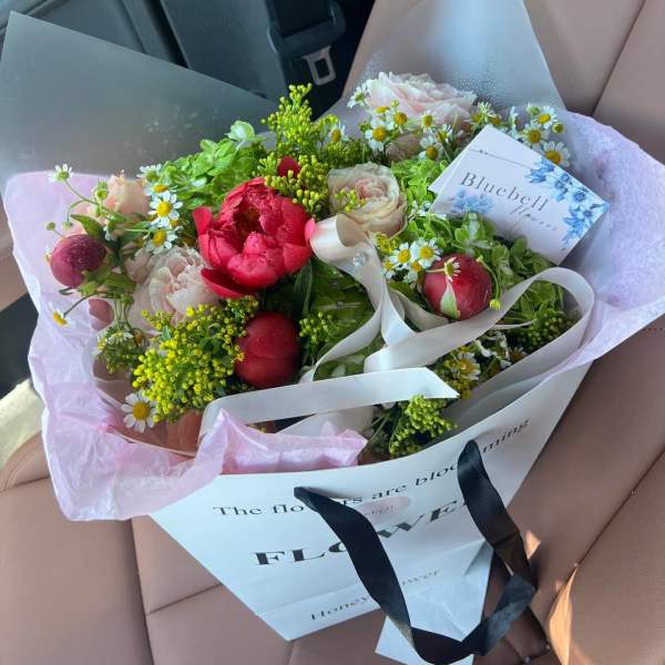 Bouquet of pink peonies and daisies wrapped in white paper
