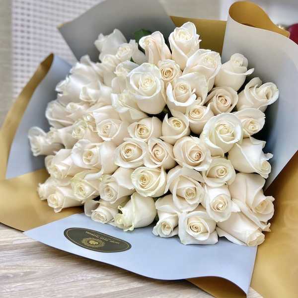 Large bouquet of cream roses wrapped in blue and gold paper