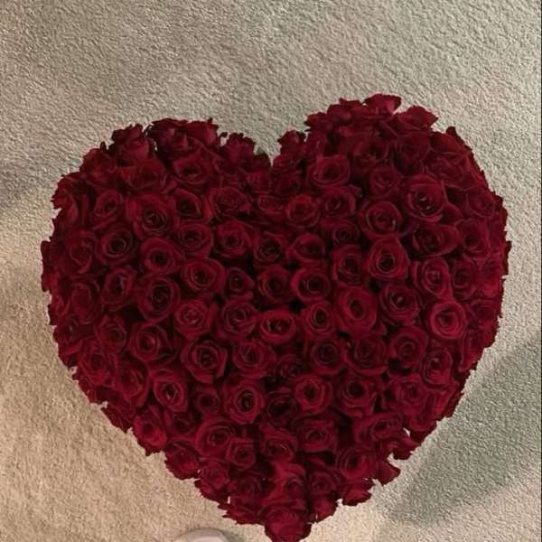 Heart-shaped arrangement of red roses on a carpeted floor