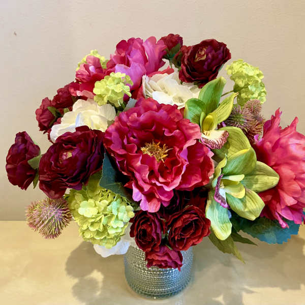 Pink and red floral arrangement in a textured silver vase