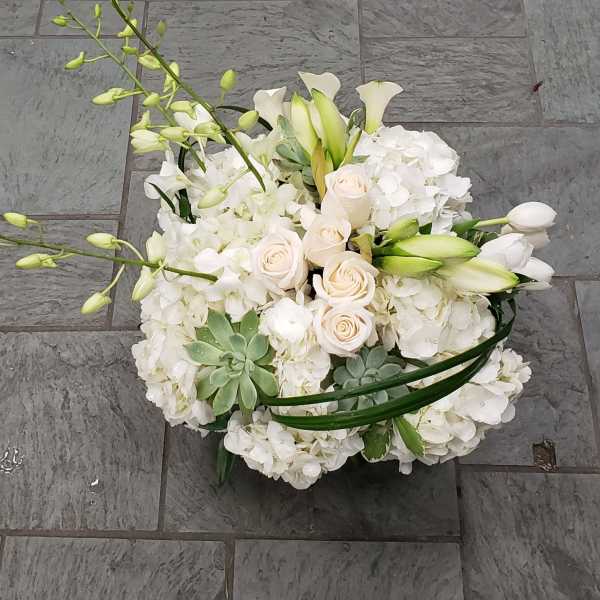 White floral arrangement with roses, orchids, and calla lilies