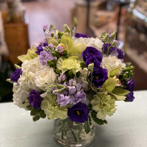 Bouquet of white, purple, and pale yellow flowers in a clear glass vase