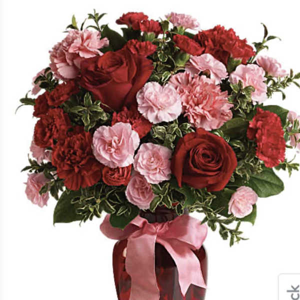 Red roses and pink carnations in a red vase with a pink ribbon