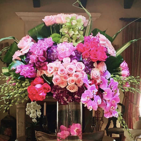 Large pink and purple floral arrangement in a tall glass vase