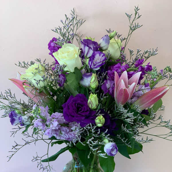 Purple and pink bouquet with roses and lilies in a glass vase