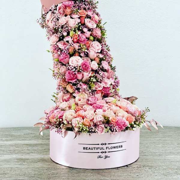 Tall pink hatbox arrangement of roses and baby’s breath