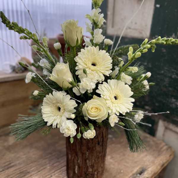 Cream floral arrangement in a rustic wooden vase