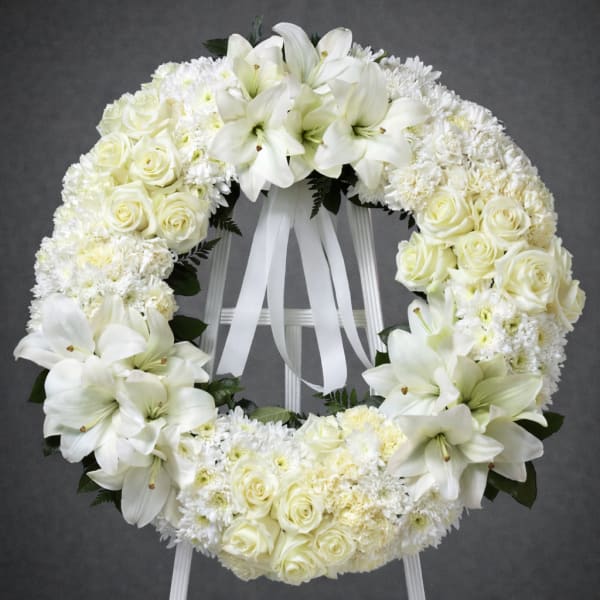 White floral wreath with roses and lilies on a stand