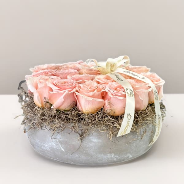 Pink roses arranged in a low silver bowl with ribbon trim