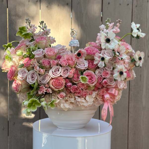 Large pink and white floral arrangement in a white bowl vase