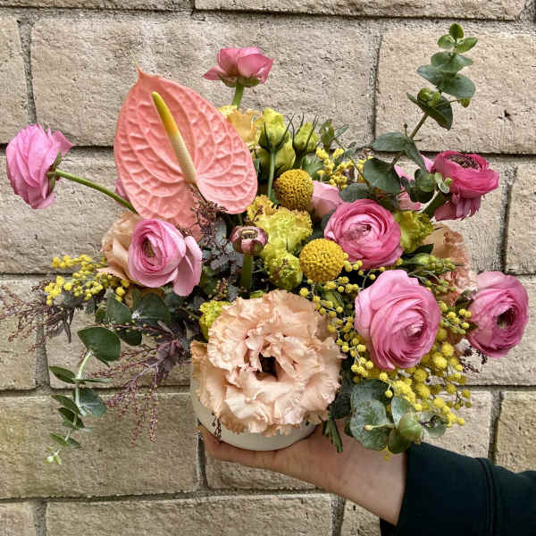 Pink and peach floral arrangement in a small white vase