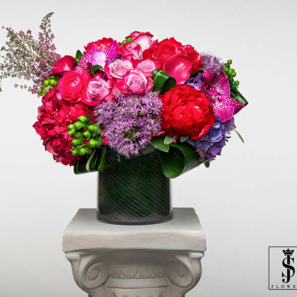 Bright mixed bouquet in a dark vase on a pedestal