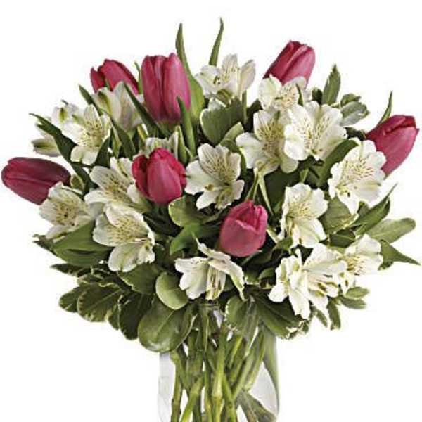Pink tulips and white alstroemeria arranged in a clear glass vase