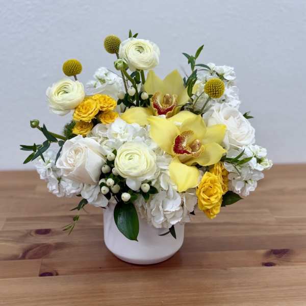 White and yellow floral arrangement in a white vase