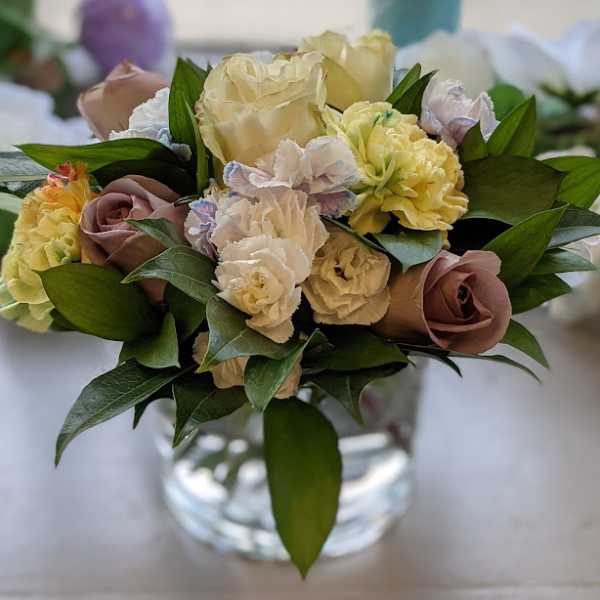 Bouquet of cream and mauve roses with pale carnations in a glass vase