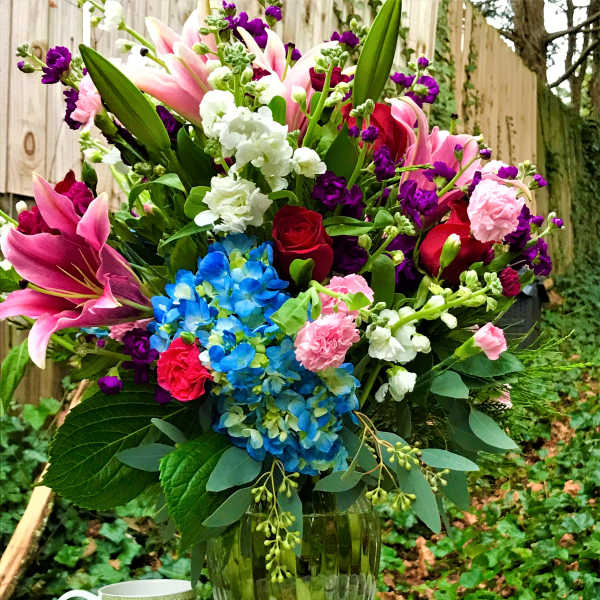 Colorful mixed bouquet in a glass vase with a mug beside it