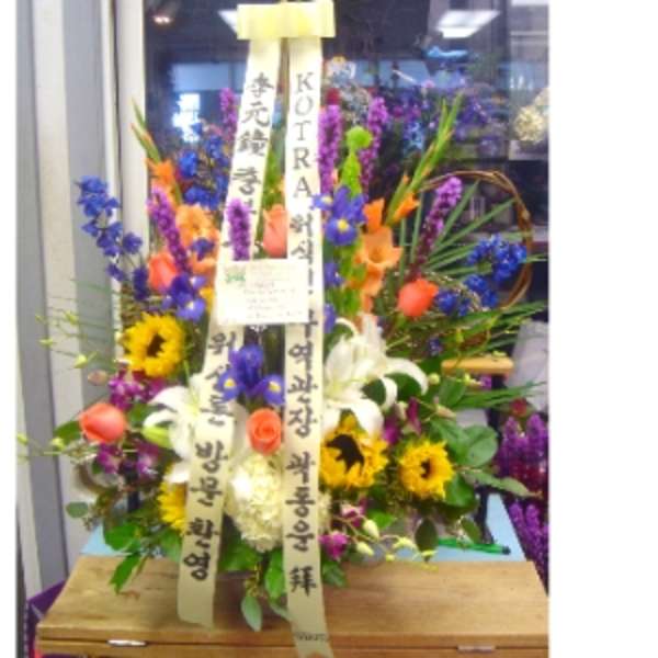 Tall mixed flower arrangement with sunflowers, lilies, roses, and irises with vertical message ribbons