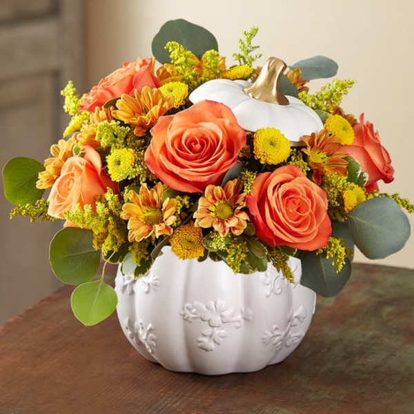Orange roses and yellow mums arranged in a white pumpkin vase