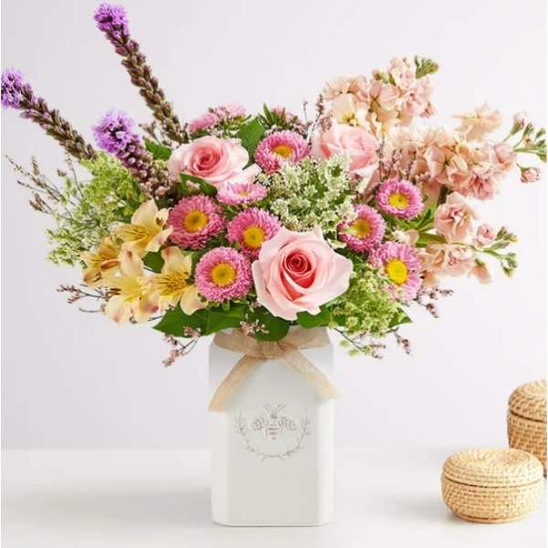 Pink and peach mixed bouquet in a white vase with a ribbon