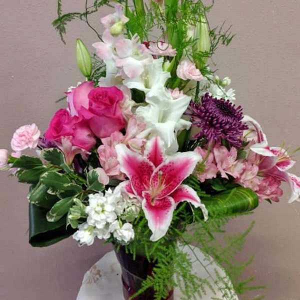 Pink and white mixed flower arrangement in a dark vase