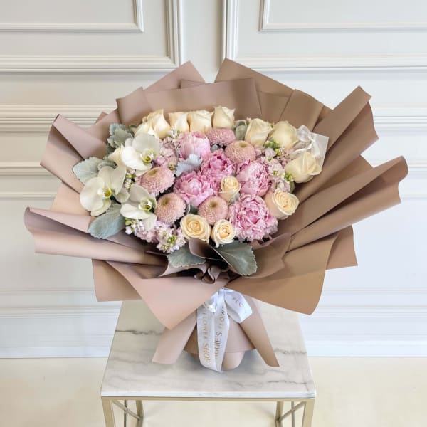 Bouquet of pink and cream flowers wrapped in tan paper