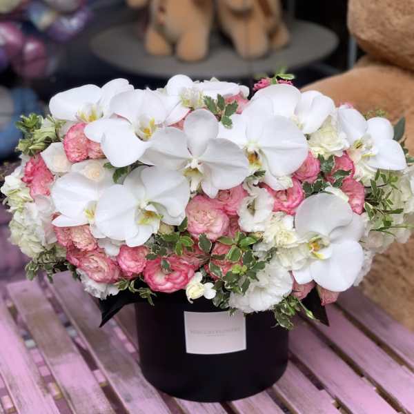 Pink and white floral arrangement in a black hat box