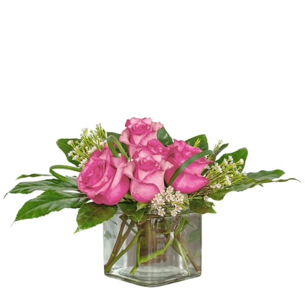 Pink roses arranged in a clear glass vase with greenery