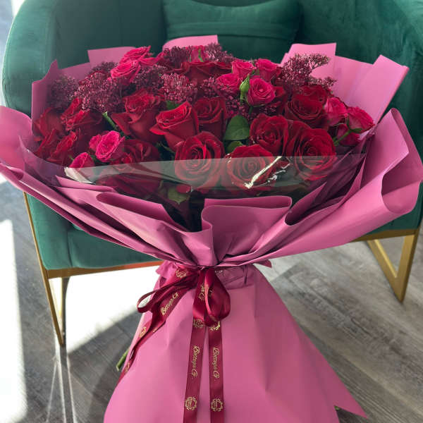 Bouquet of red roses wrapped in pink paper with a ribbon