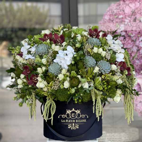Large floral arrangement in a black hatbox with white, green, and burgundy blooms
