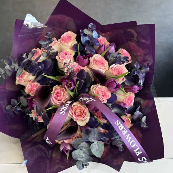 Bouquet of pink roses and purple tulips wrapped in dark purple paper