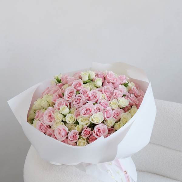 Large bouquet of pink and white roses wrapped in white paper
