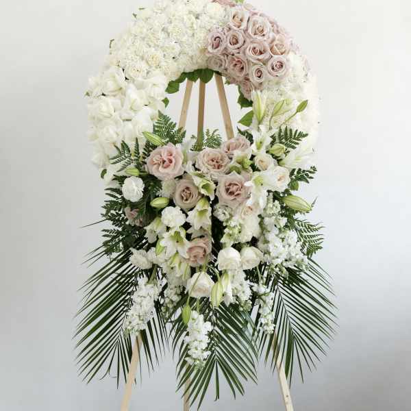 Large white and blush floral wreath on a wooden stand