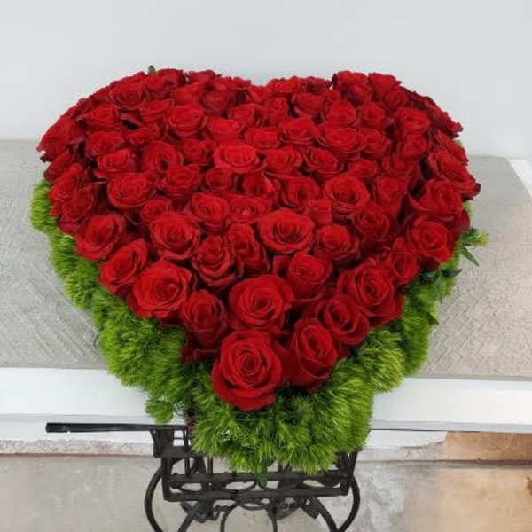 Heart-shaped arrangement of red roses with a green border