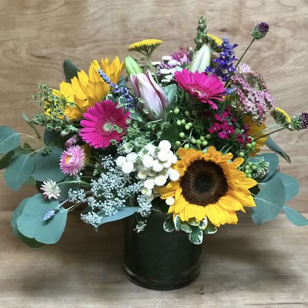 Mixed bouquet with sunflowers, pink gerberas, and a dark vase
