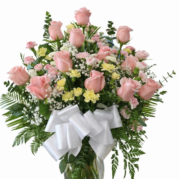 Pink roses and mixed flowers in a glass vase with a white bow