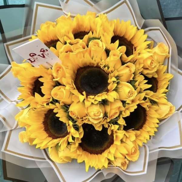 Bouquet of yellow sunflowers and roses wrapped in white paper