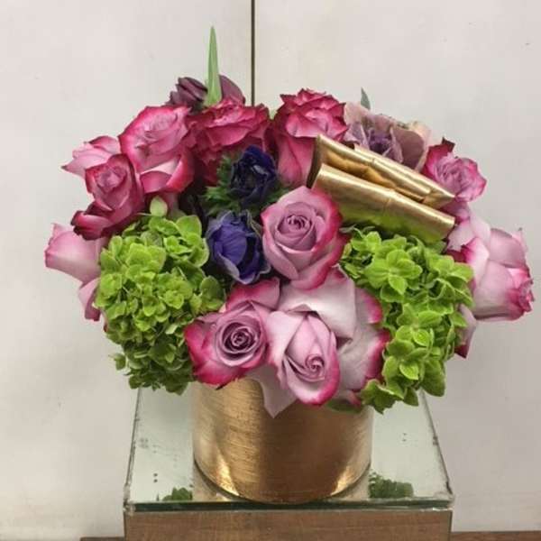 Pink and purple roses with green hydrangeas in a gold container