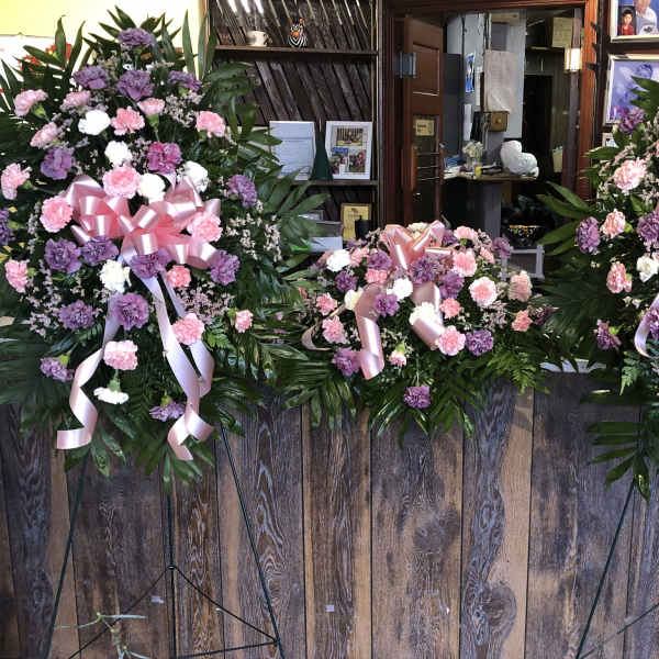 Three pink and purple standing floral sprays with ribbon bows