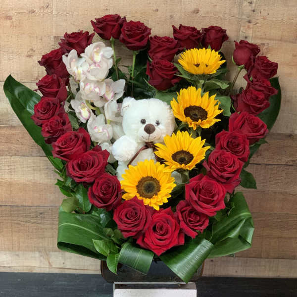 Heart-shaped bouquet of red roses, sunflowers, orchids, and a teddy bear