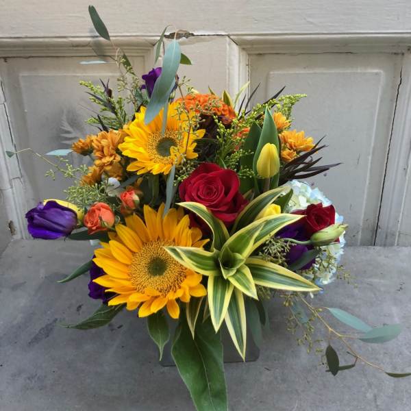 Mixed bouquet with sunflowers, roses, and tulips in a vase