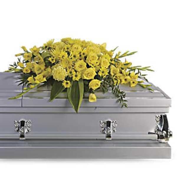 Yellow floral casket spray arranged on top of a closed silver casket