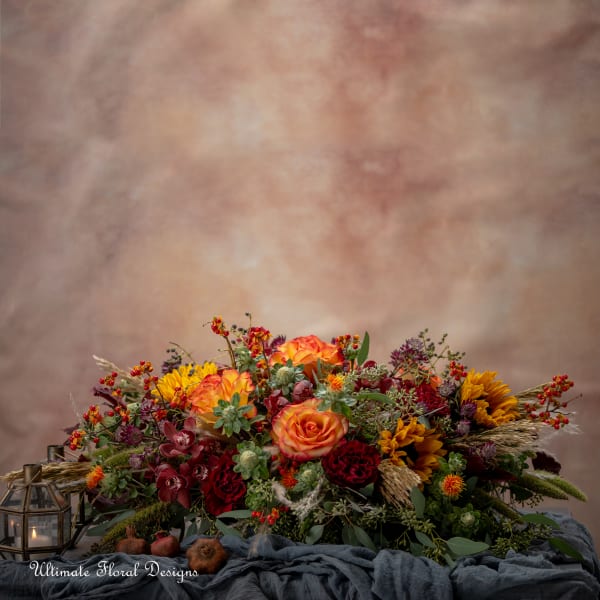Low floral centerpiece with orange roses, sunflowers, and red blooms