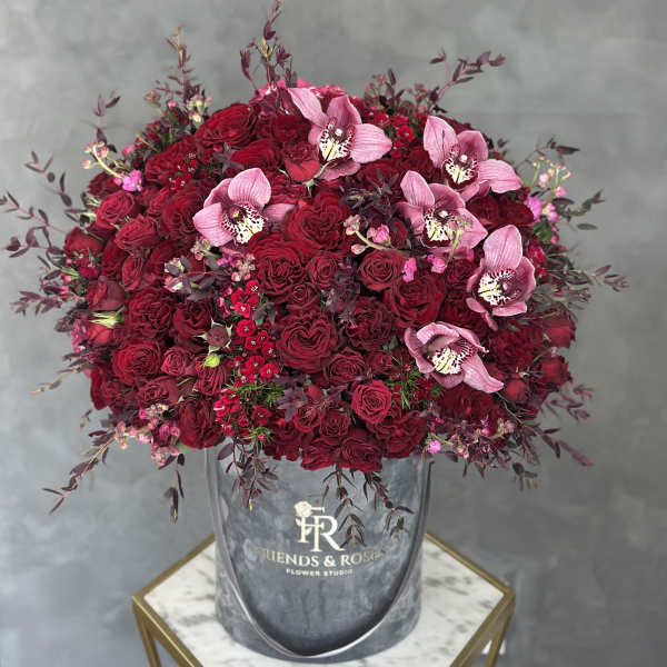 Large bouquet of red roses and pink orchids in a gray hatbox