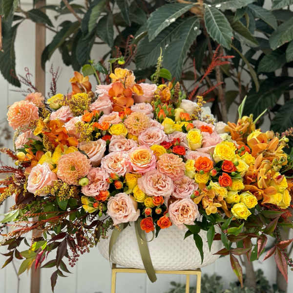 Large mixed floral arrangement in a white bowl vase with pink, yellow, and orange blooms