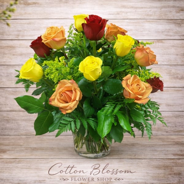 Bouquet of yellow, peach, and red roses in a clear glass vase