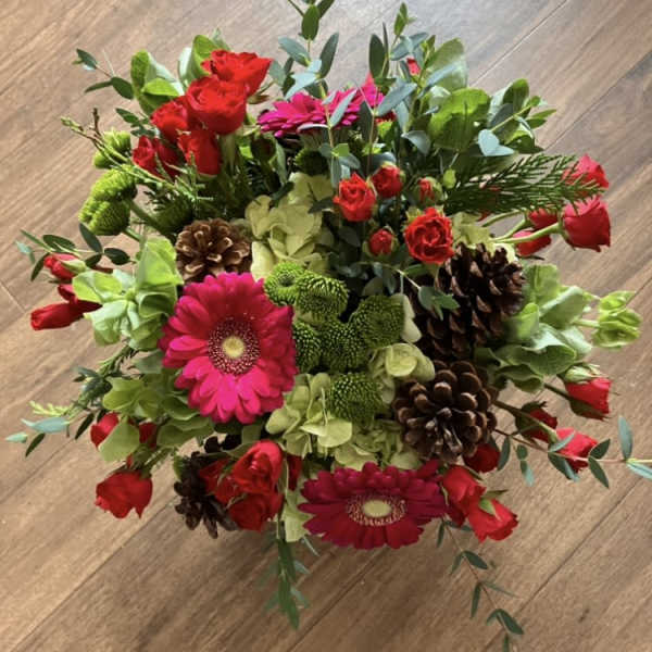 Bouquet of red roses, pink gerbera daisies, and green hydrangeas with pinecones