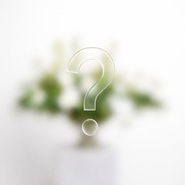 Blurred green-and-white floral arrangement with a large question mark overlay
