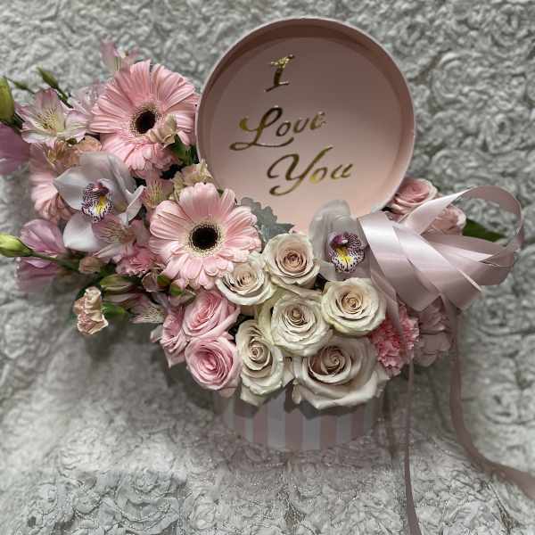 Pink and white flower arrangement in a round box with a "I Love You" lid