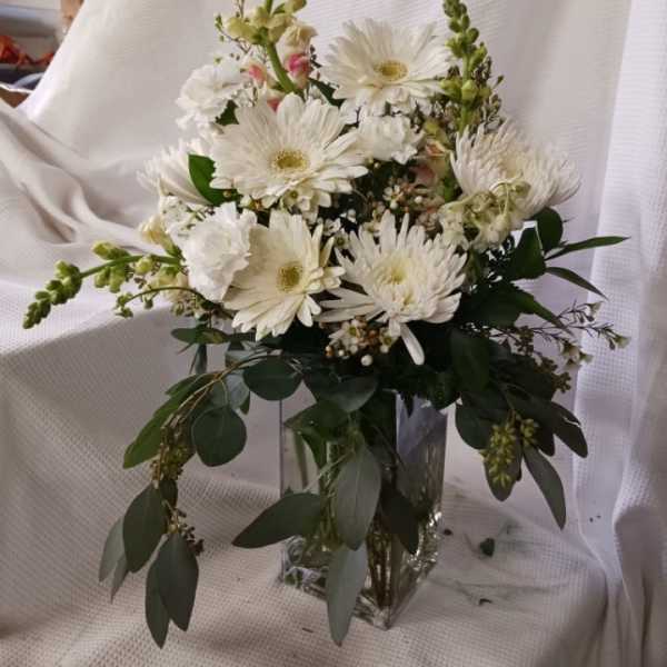 White gerbera daisies and snapdragons in a clear glass vase