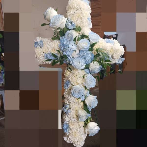 White and pale blue floral cross arrangement on a stand